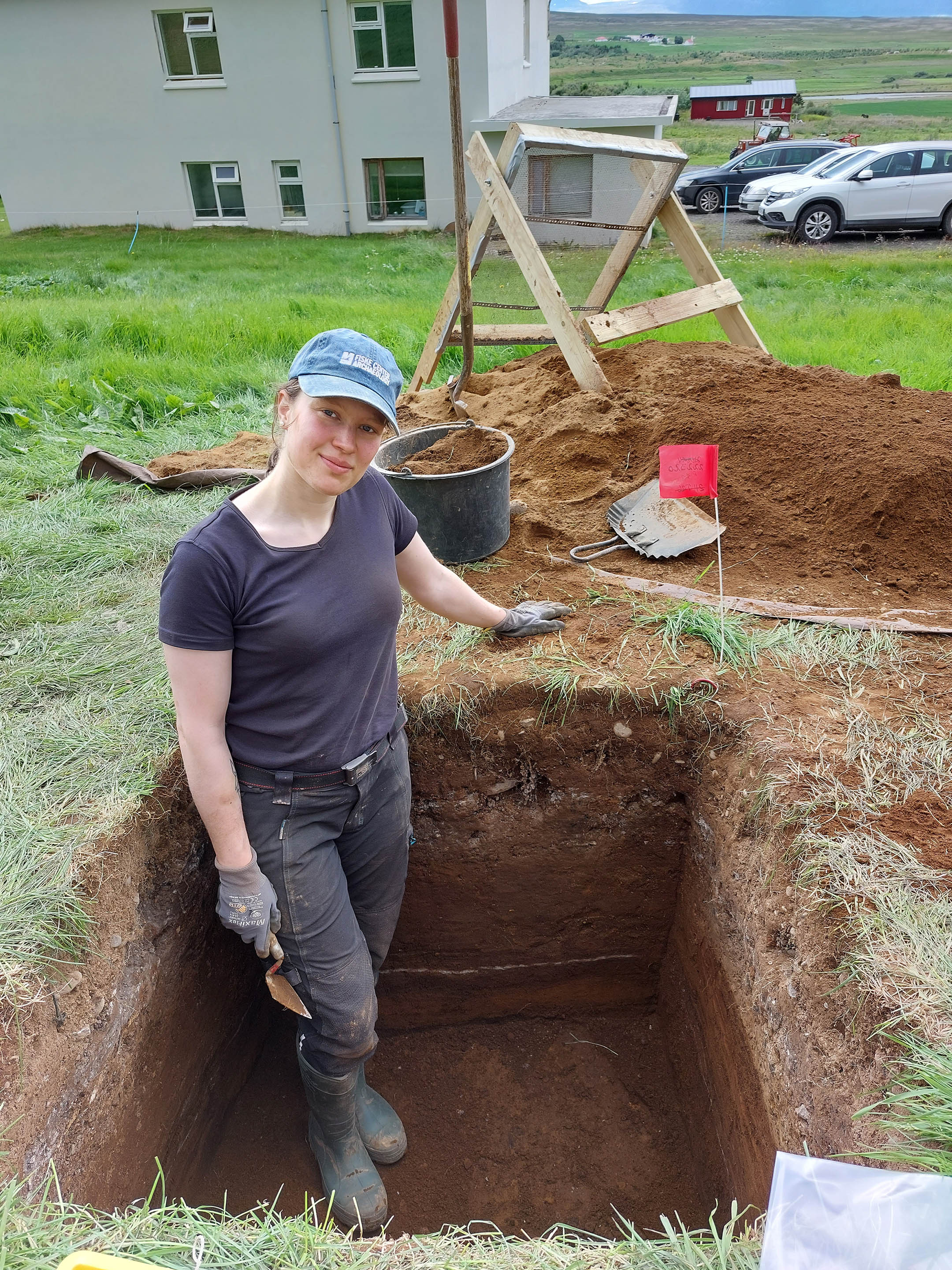 Ylfa Leifsdóttir í skurði í öskuhaug á Neðra-Ási. Í sniðinu má sjá hvíta línu, gjósku úr Heklu frá 1104.